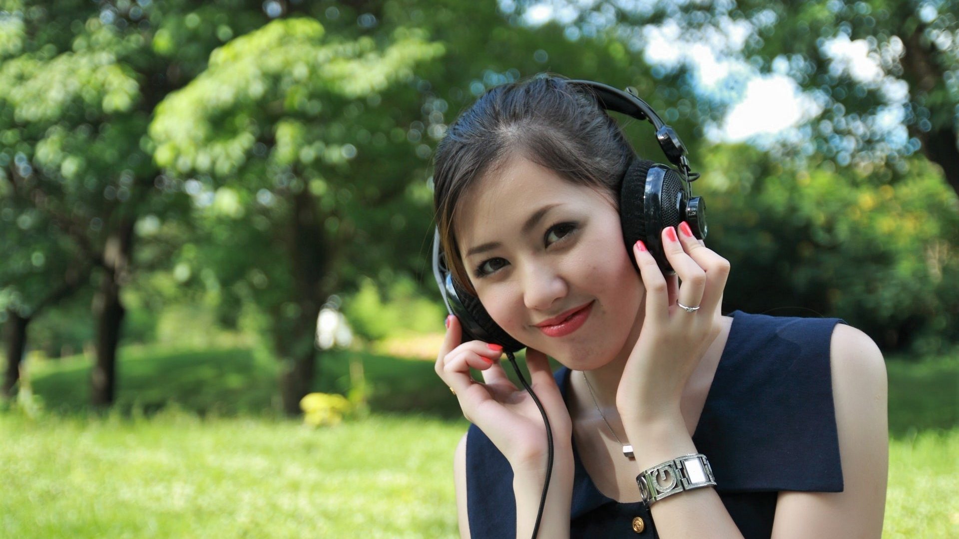 Slečna sedící v parku se sluchátky na uších